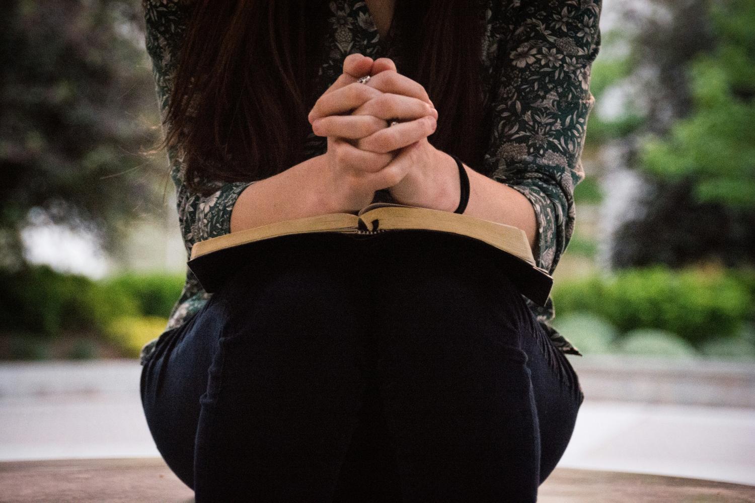 Woman praying with bible in her lap - Olivia Snow